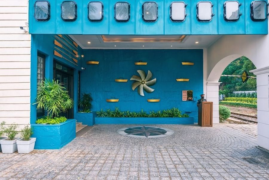 Another angle of the hotel's entrance during the day with a focus on the blue facade and the nautical-themed propeller decoration.
