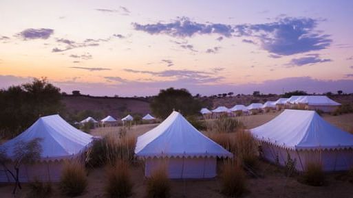 image of the tents at manvar resort and desert camp with mesmerising sunset with lavender and orange hues in the background - MANVAR Resort & Desert Camp
