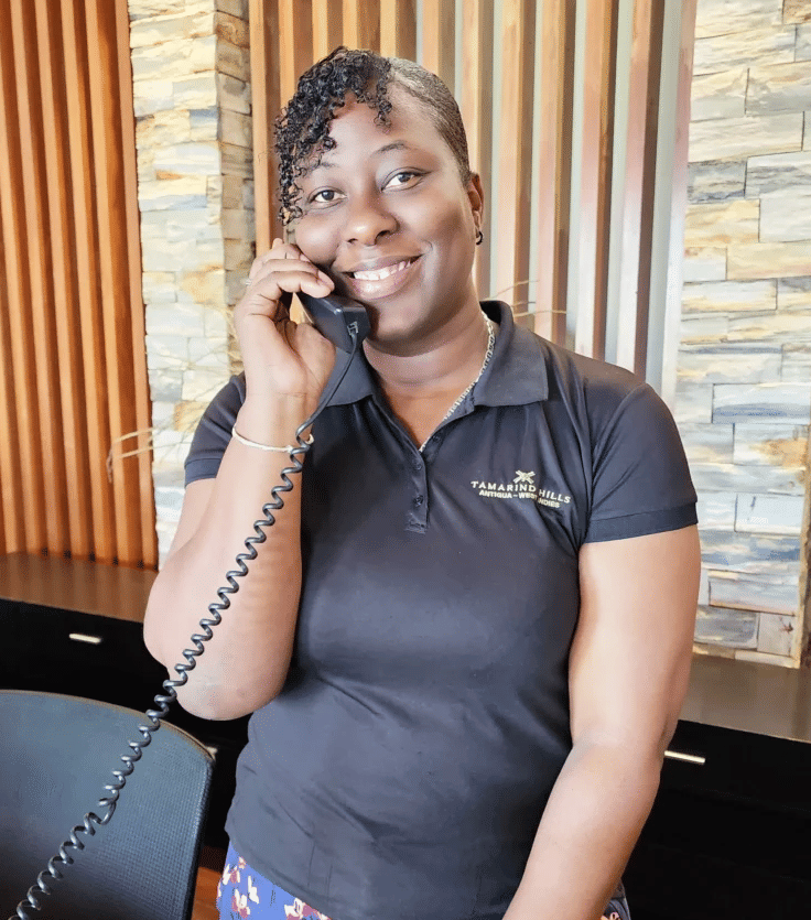 Resort staff member cheerfully holding the phone at the reception desk.