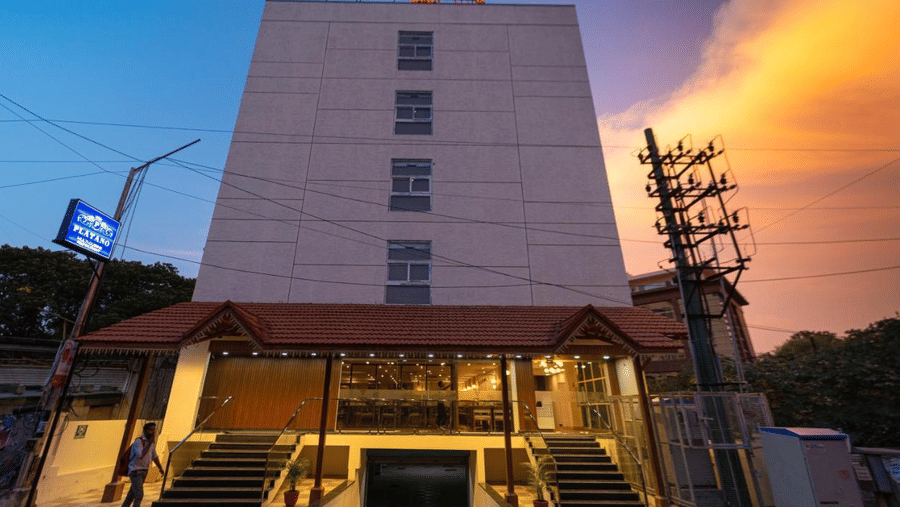 The facade of VITS Select, Bengaluru as seen from the front, featuring stairs leading up to the hotel with a vibrant sky in the background.