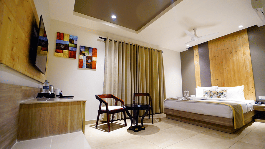 Wide view of a room at Five Elements Hotel with a king bed, colourful wall art, wooden headboard, ceiling fan, and bright natural light.