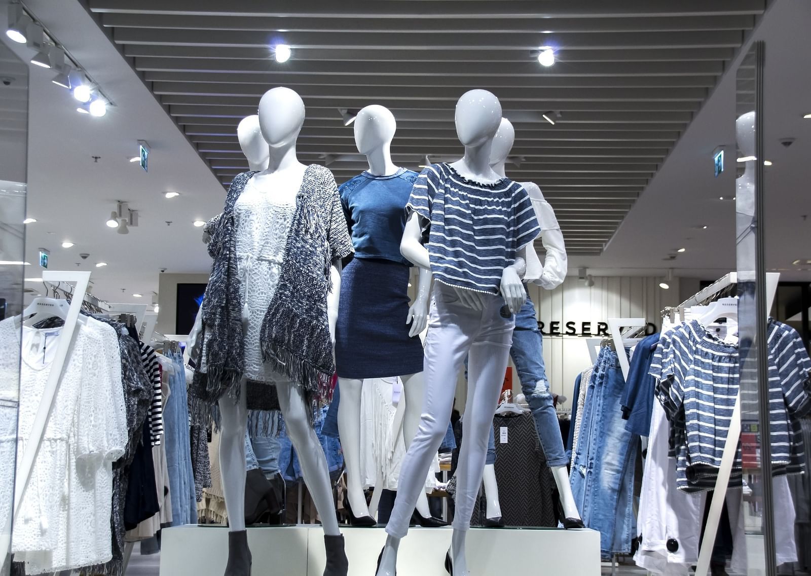 An overview of a shop with women mannequins displaying new clothes.