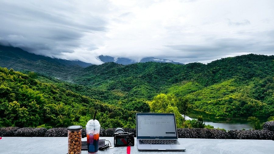 a laptop and other accessories set on a balcony overlooking lush mountains