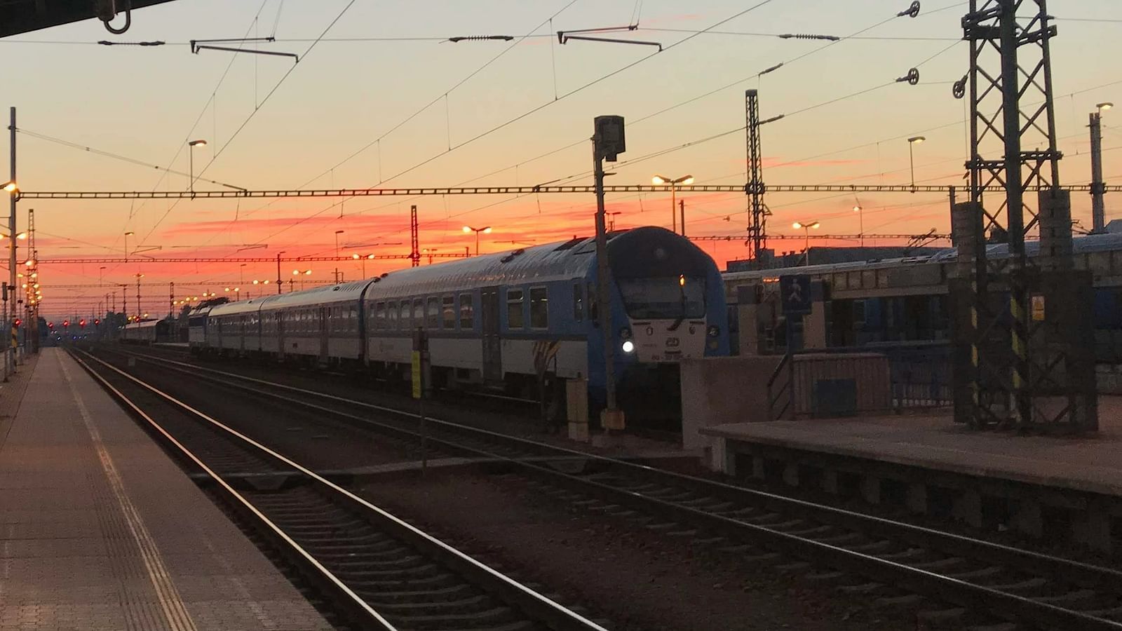 An overview of a train station with different hues in the sky in the background