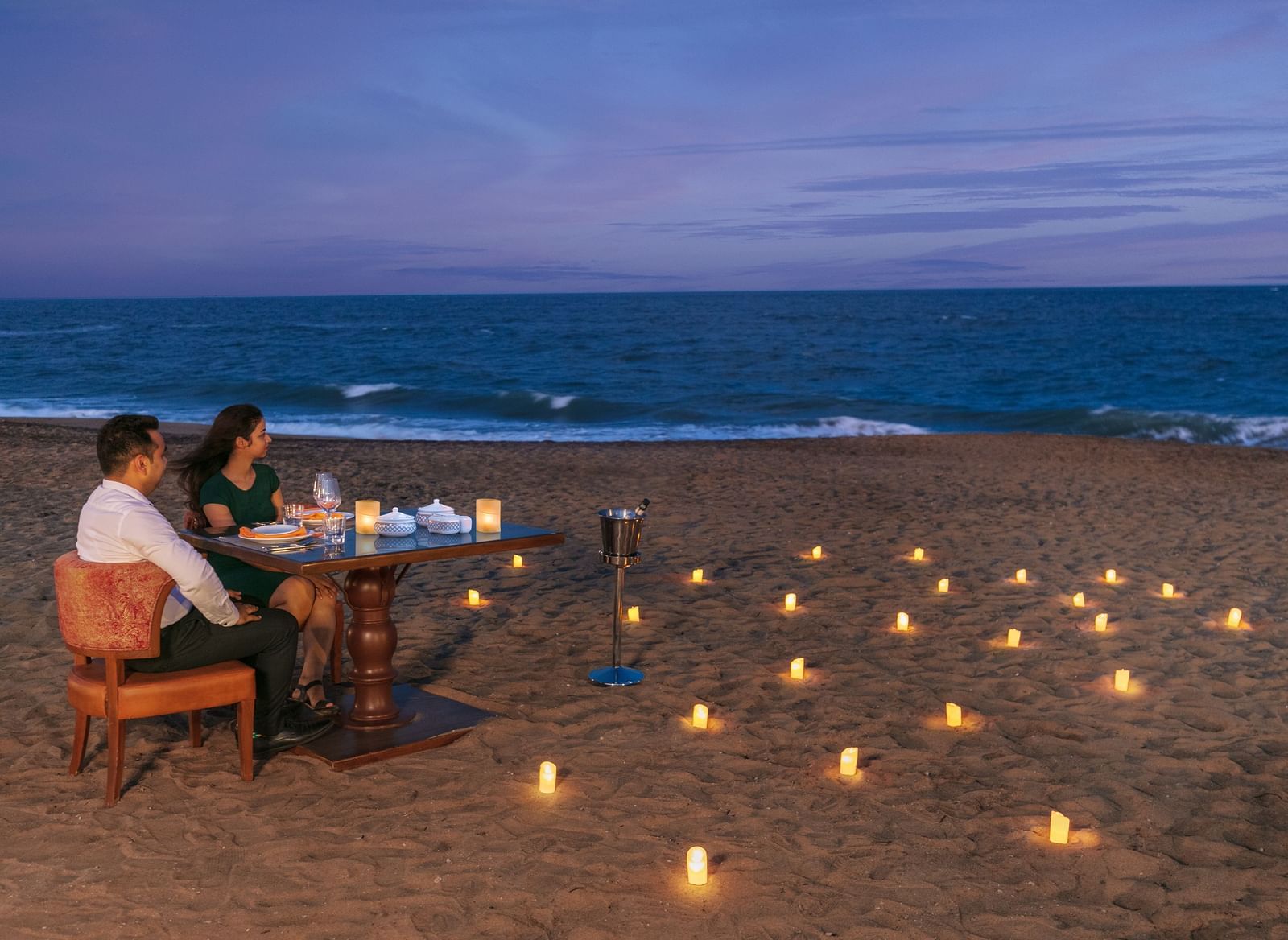 A romantic candlelight dinner setup on a pristine sandy beach – Kaldan Samudra Palace, one of the top 5 Star Restaurants in Mahabalipuram ECR, offering an unforgettable dining experience by the sea