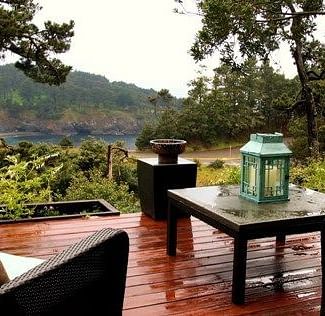 A deck with couches, a teapoy and surrounded by lush greenery - Brewery Gulch Inn & Spa