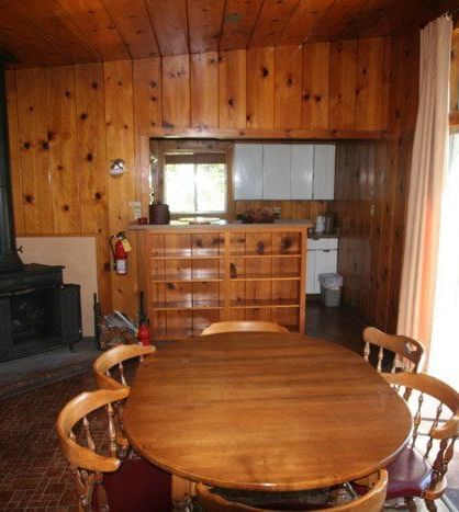 The interior of a rustic cabin features wood-paneled walls, a round dining table, and a fireplace | Polar Bear