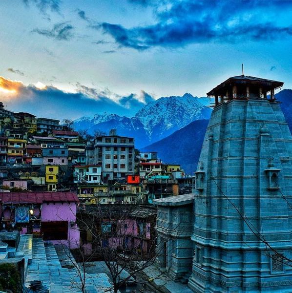 image featuring the top portion of a temple with the landscape of a city with small houses