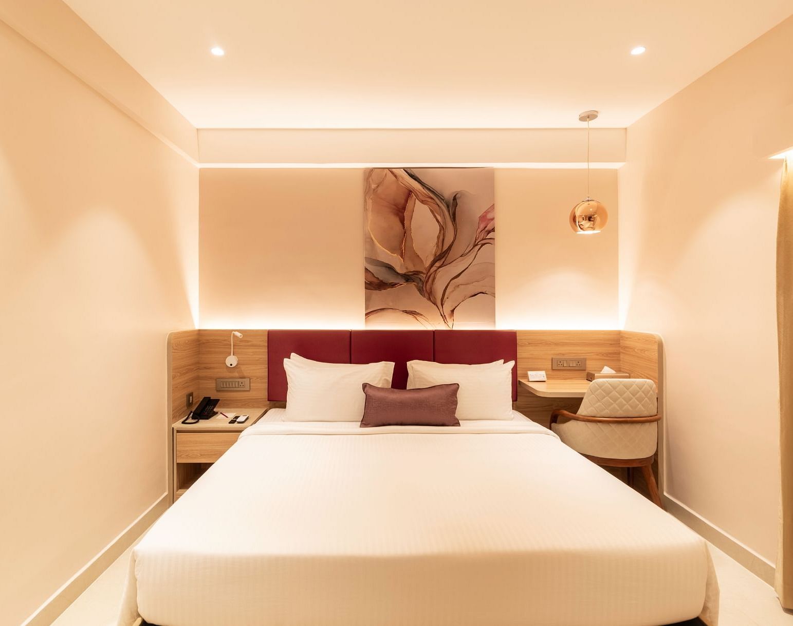 King-sized bed with wall art in The Executive Rooms at TGI Livancia The Sojourn, Bangalore.