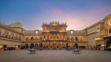 A facade image of Chomu Palace Hotel with the backdrop of a serene sunset
