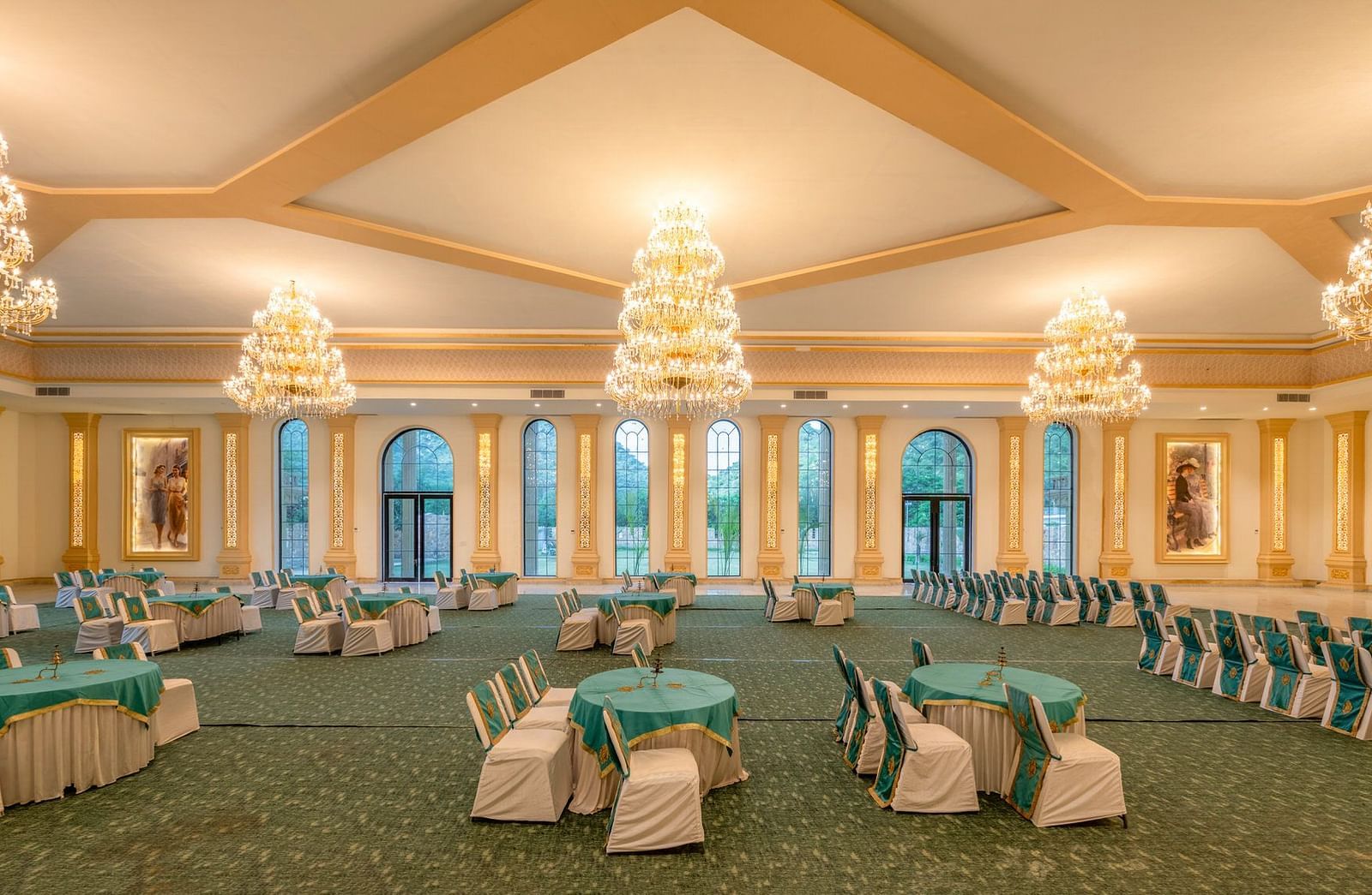 Side view of a banquet hall featuring round tables with chairs and chandeliers elegantly hanging from the ceiling at Valley by Grassfield.