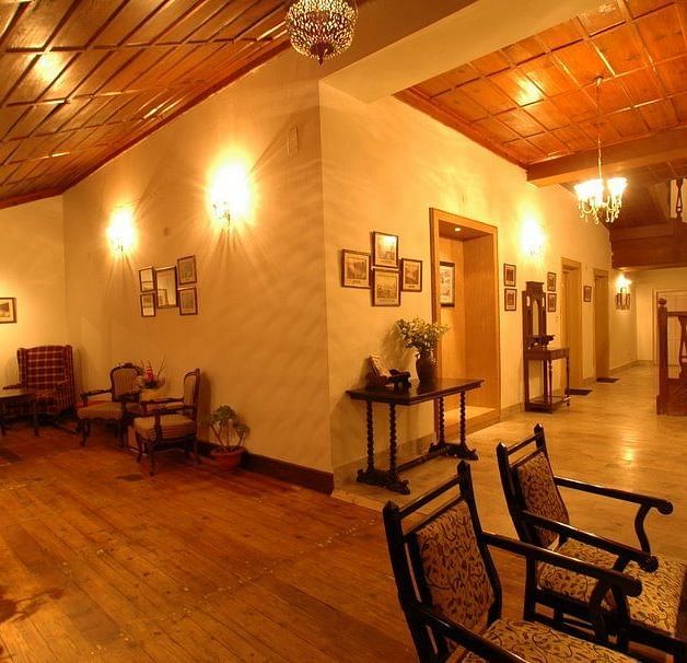 An image of a rooms with timber floors, adjacent to each other, these rooms have wooden chairs and tables with a few flower pots around