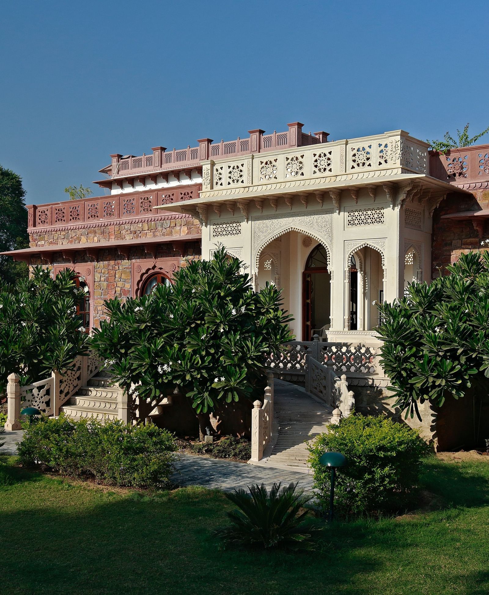 A traditional Indian palace or large building with lush gardens under a clear sky - Khas Bagh, Jaipur.