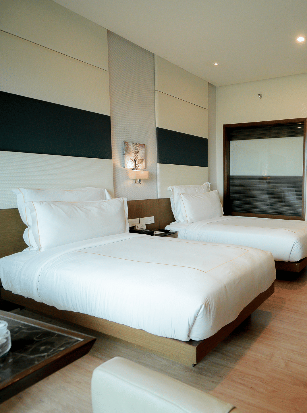 Spacious hotel room with plush twin beds and a work area – Narayani Heights Hotel & Resorts