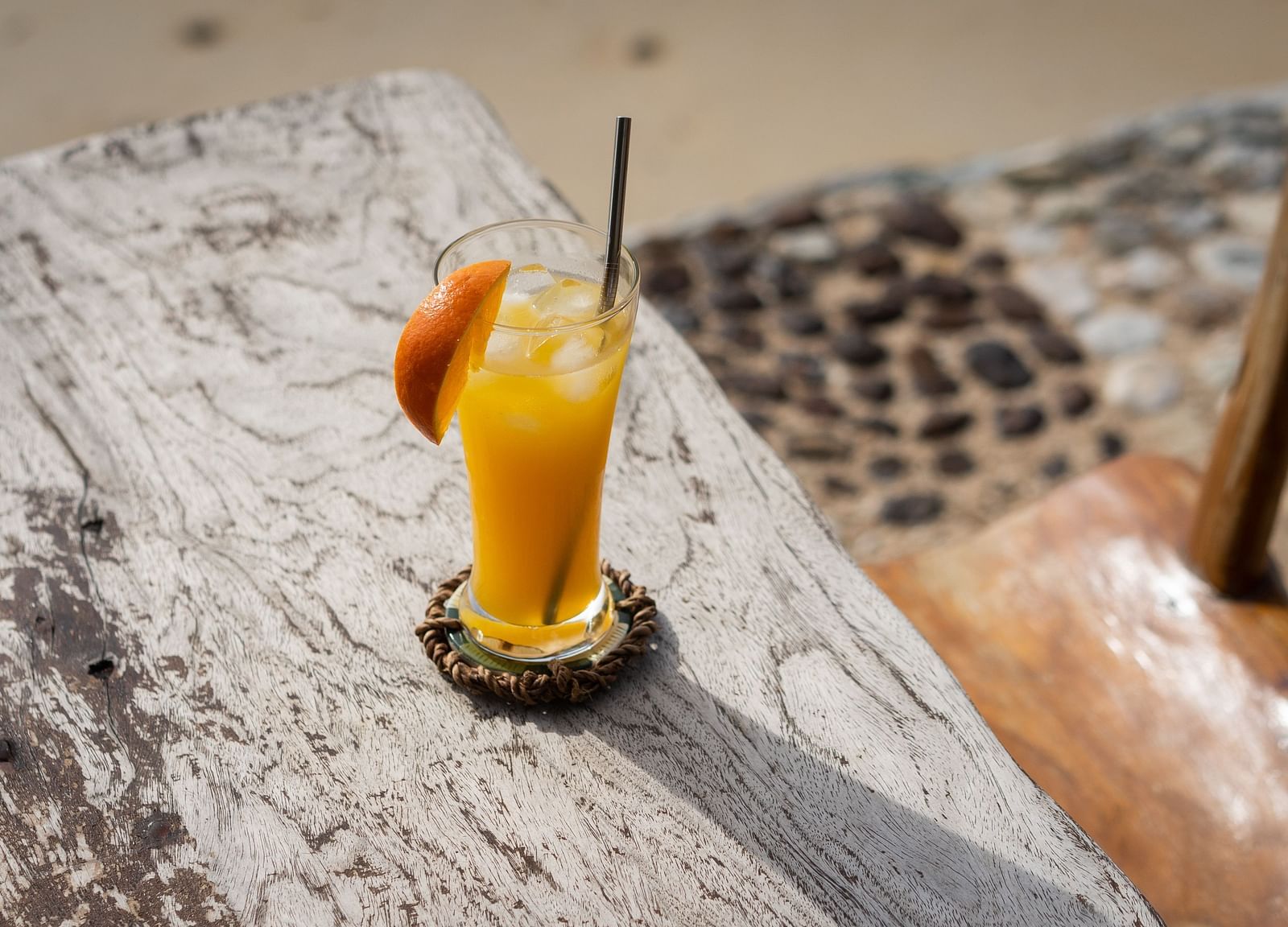 Orange tropical drink served in a glass on a rustic wooden table at Flower Island Resort.