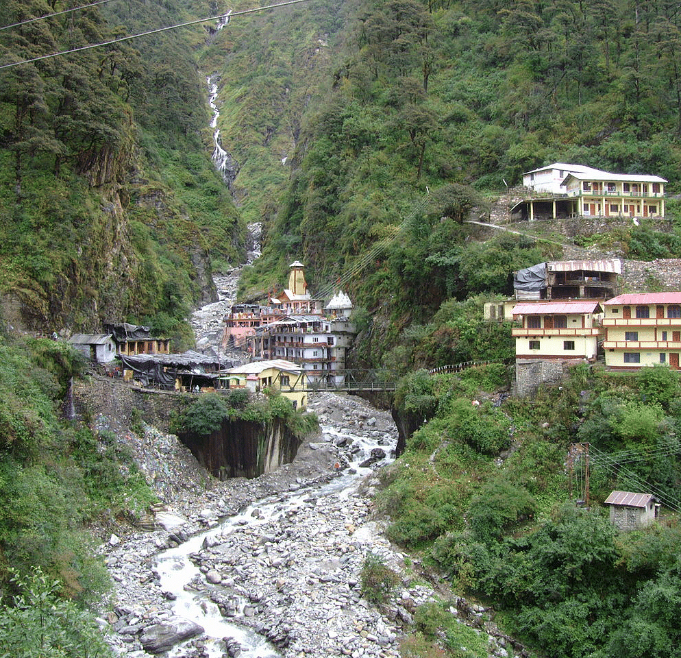 A beautiful picture of a stream with mountains in the background with a few buildings