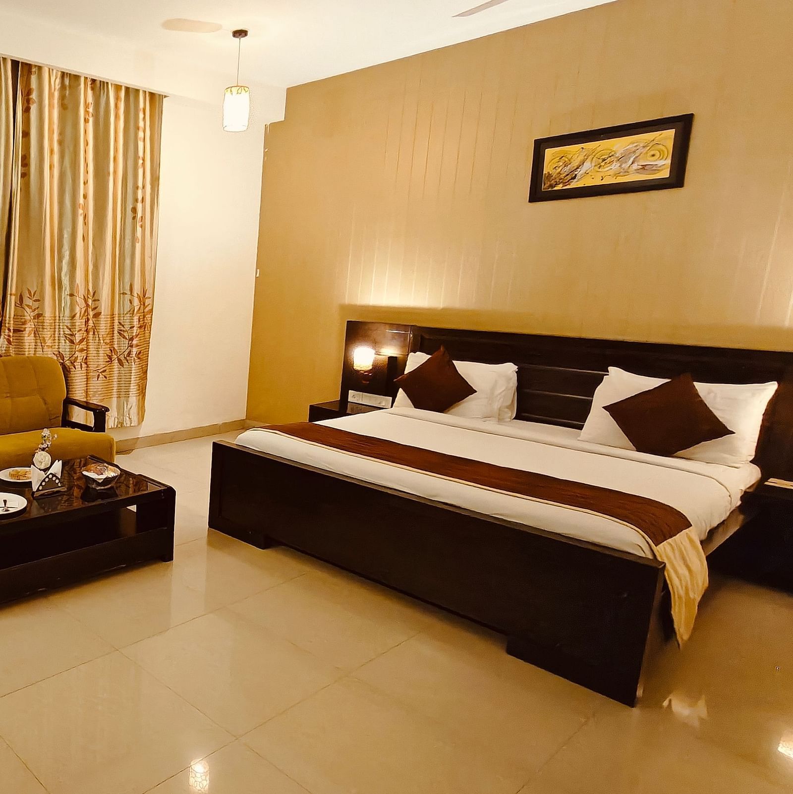 Suite with king size bed room with sofa, side tables, and warm lighting at Hotel Alps Residency, Krishnagiri.