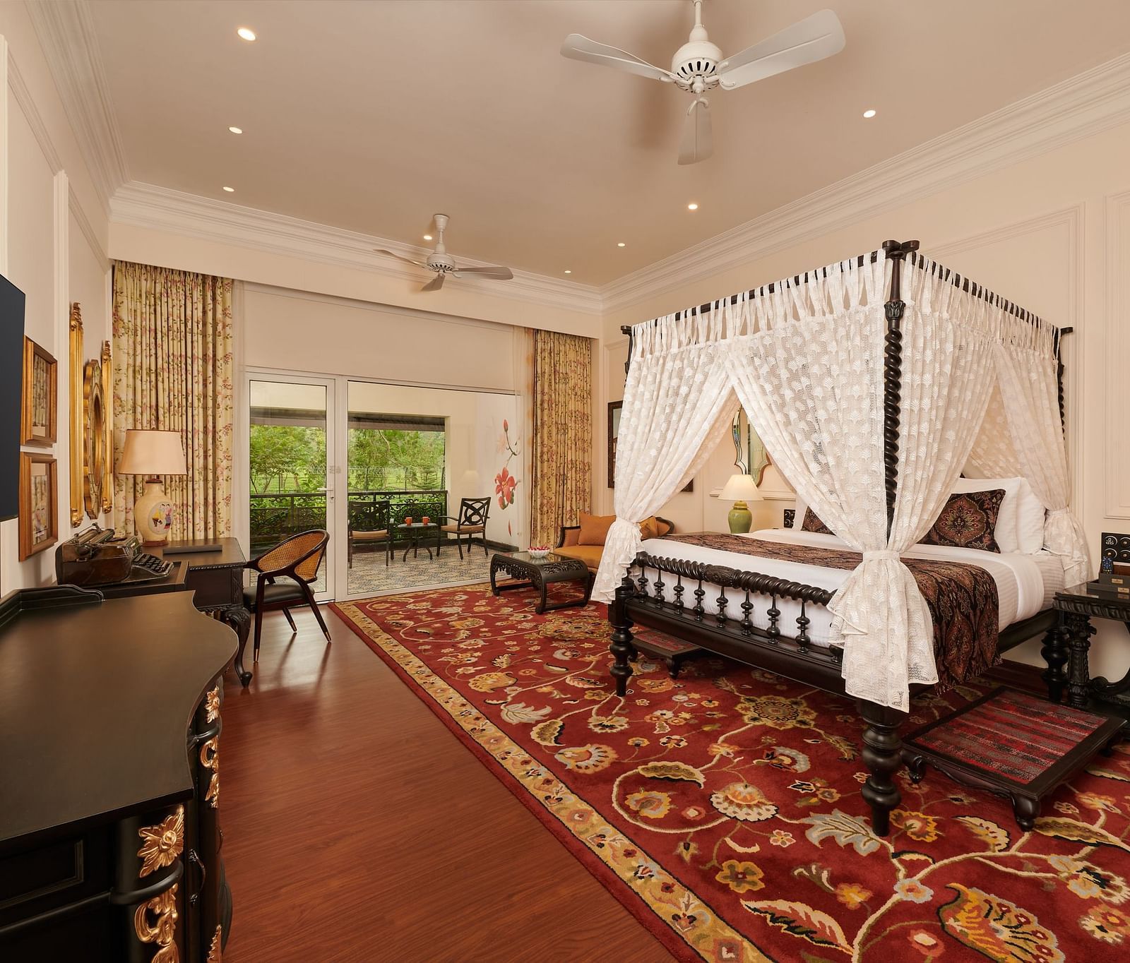 Four-poster bed in a spacious suite with vintage decor and carpeted flooring.