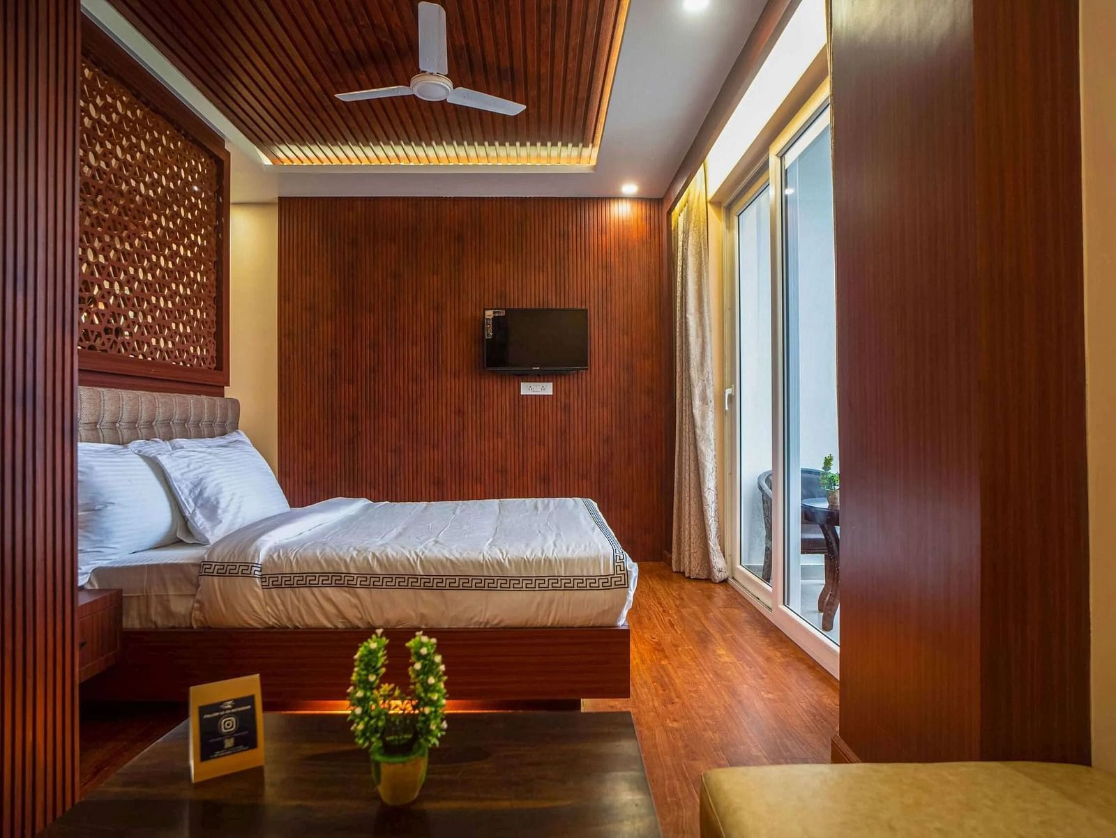 A stylish room at Mansha Palace offers a comfortable bed, a coffee table, a TV, and balcony access.