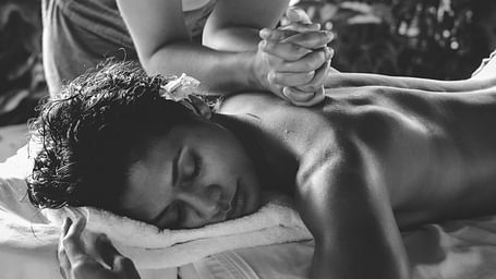 A woman getting a back massage from a masseuse's elbows