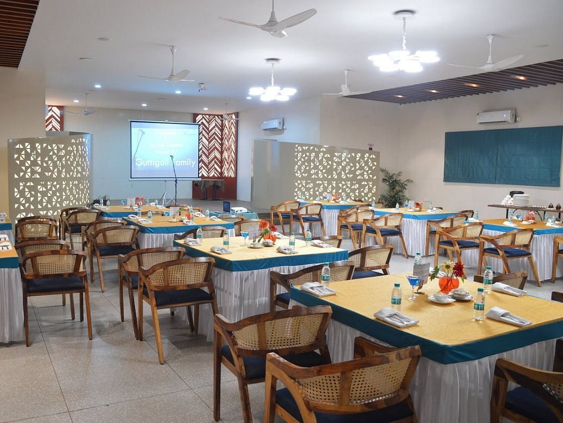 Council Hall at Lords Eco Inn Belagavi, set up with round tables, elegant décor, and a projector screen for conferences