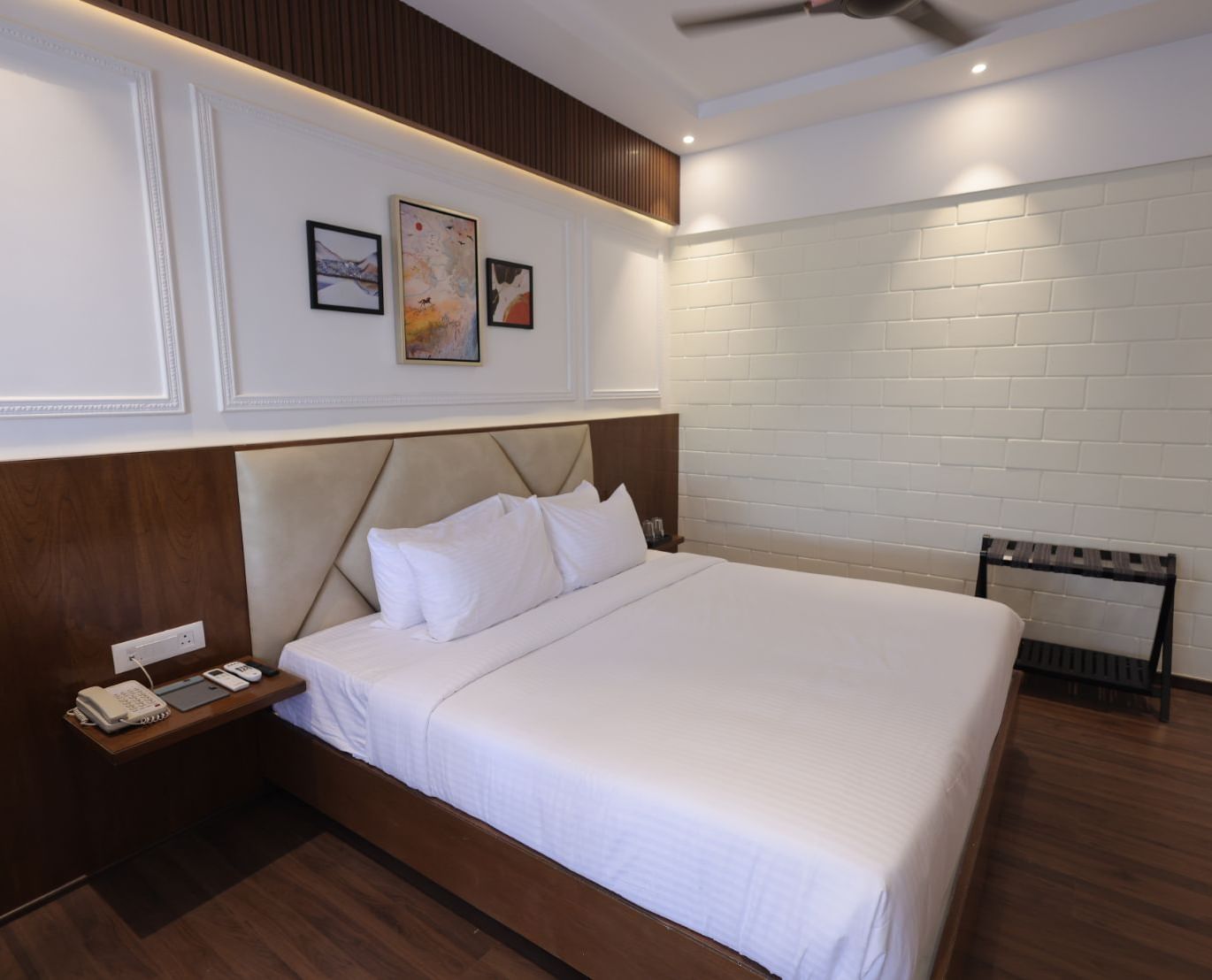 A room with double bed, bedside table and framed art work at Trishvam Symphony, Krishnagiri