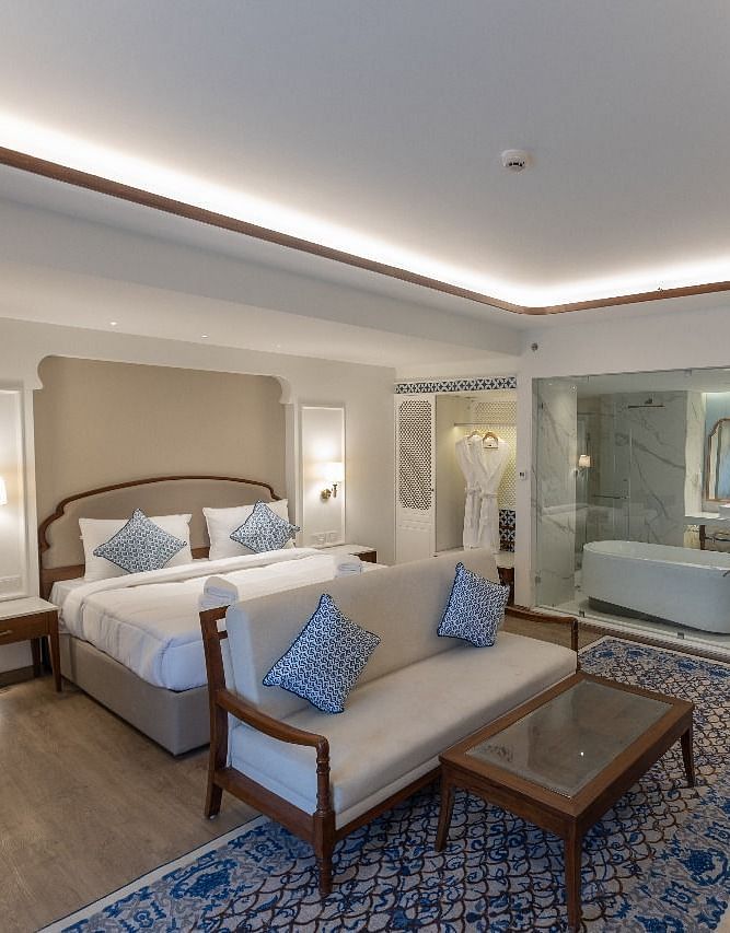 Full view shot of the Purna Room at Bhagirathi by RDB Atishay featuring a double bed and a couch in front of it at Bhagirathi by RDB Atishay. 