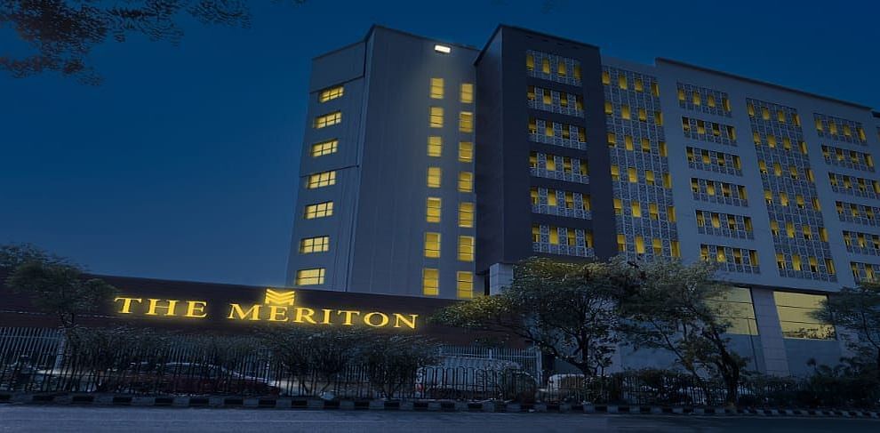 Facade shot of The Meriton in New Delhi during the night time with a well illuminated neon board in the front.