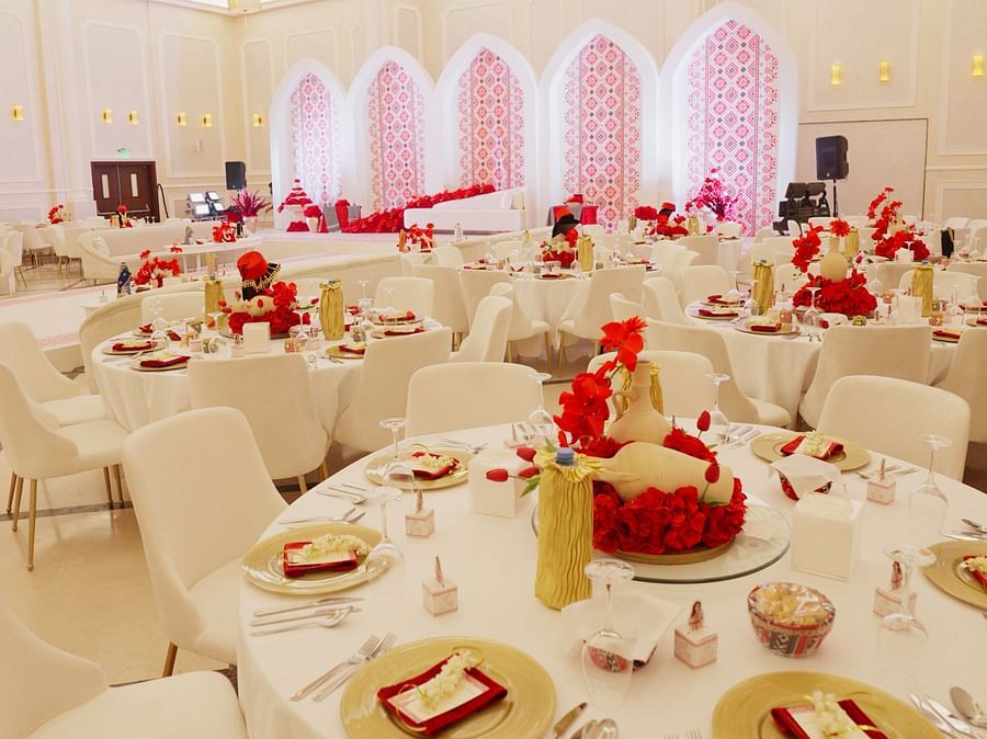 A narrow, vertical view of a decorated banquet hall at La Maison, Doha, showing tables set for dining.