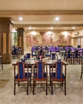 A large dining area is prepared with numerous tables and blue chairs - Lion Lords Inn Rajula