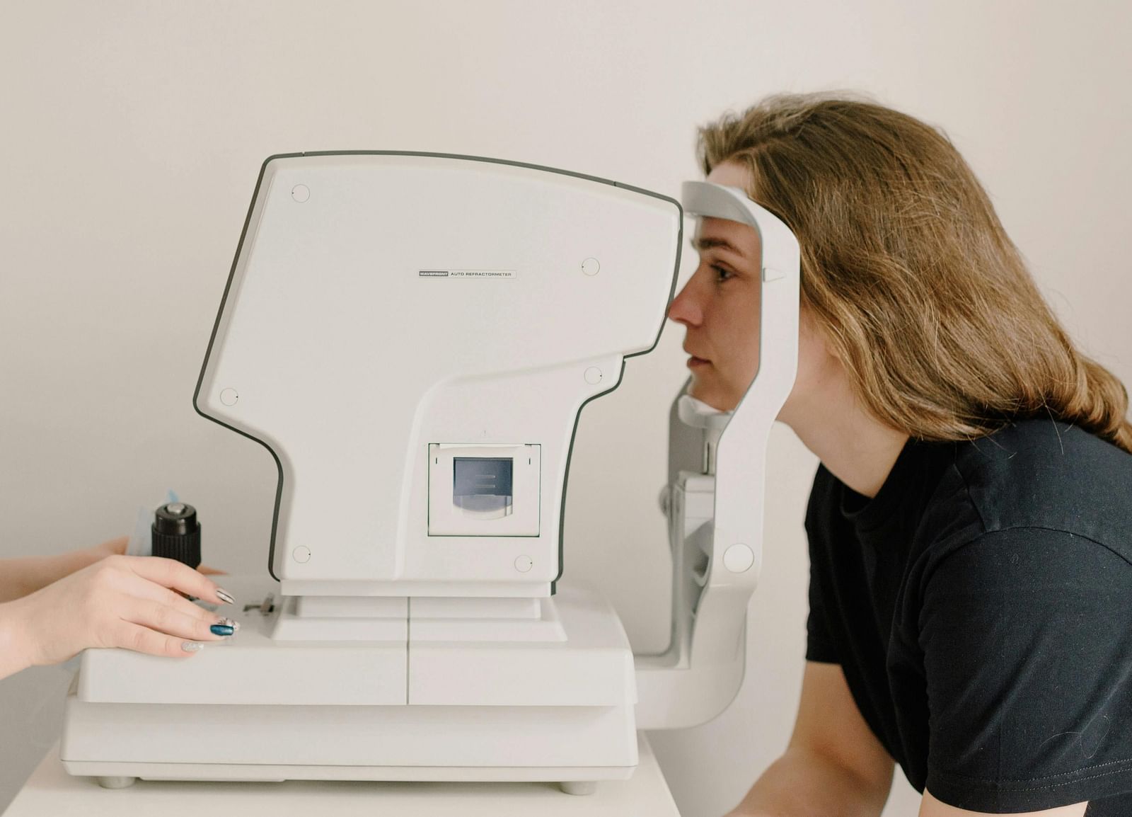 A woman undergoing an eye examination using an automated refractometer machine.