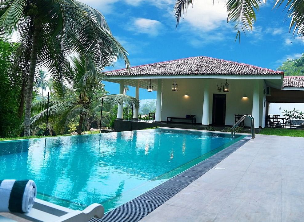  A stunning outdoor pool surrounded by tropical plants and palm trees, offering a tranquil and relaxing setting for guests.