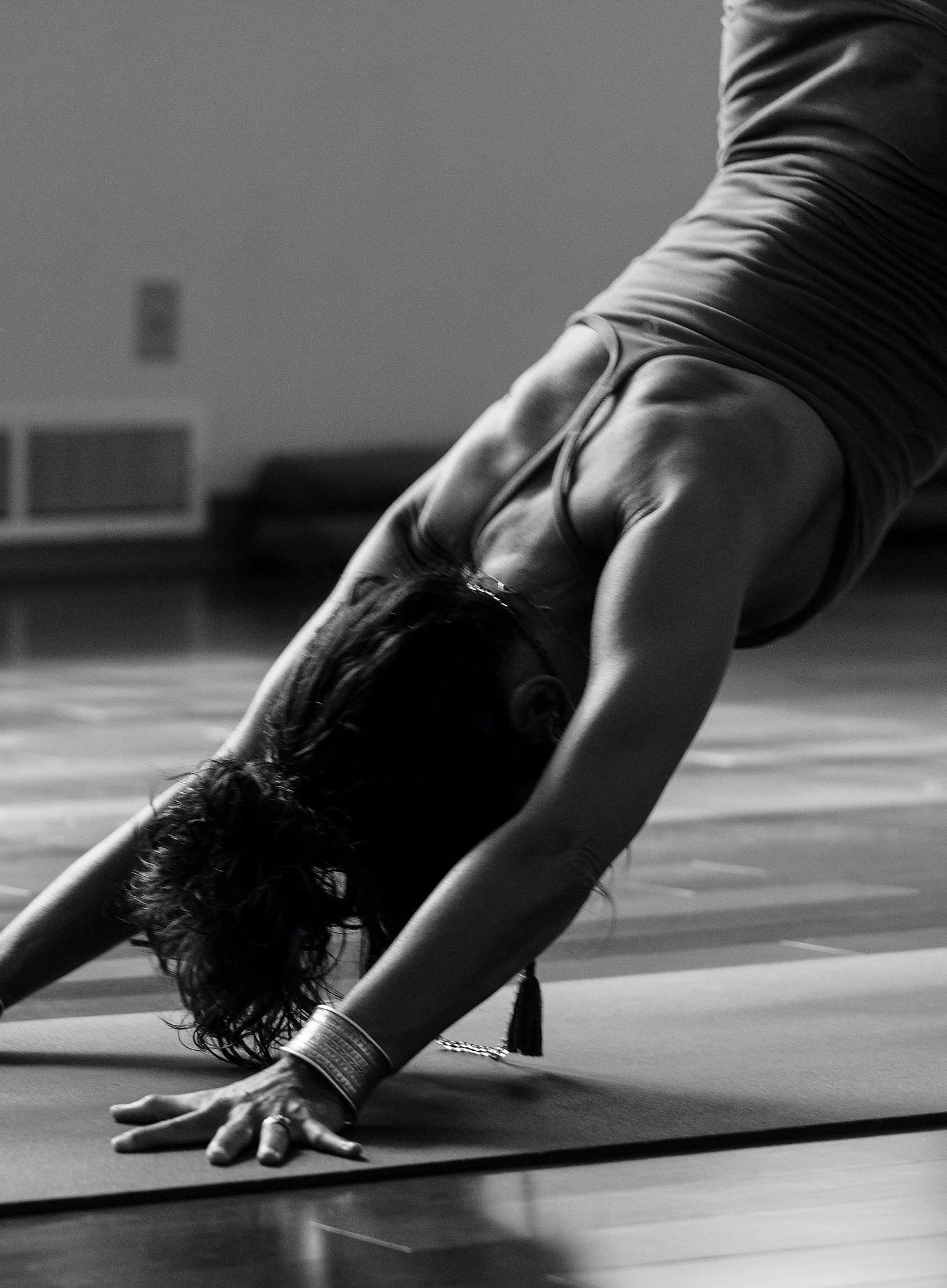 a black & white image of a woman doing yoga stretches on a yoga mat