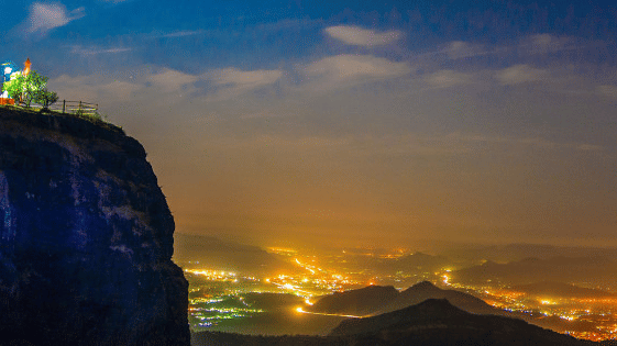 a panoramic view from a hill under vibrant sky showcasing the lit city