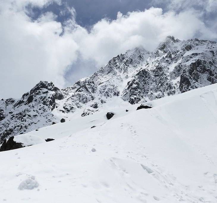 Image of a snow clad mountain with coulds in the background 