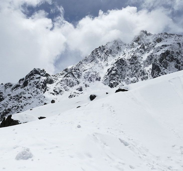 Image of a snow clad mountain with coulds in the background 