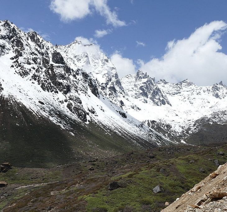 Image of mountain peaks covered with snow and greenery on the foothill of the mountians.
