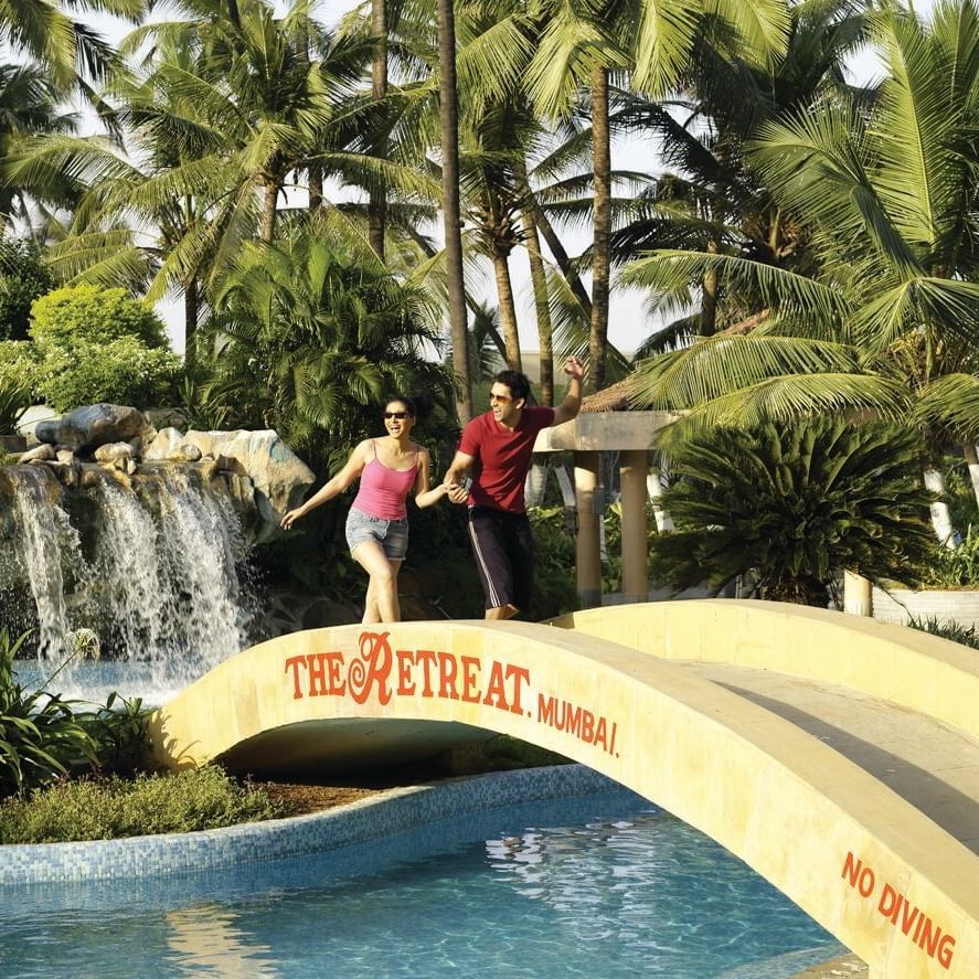 A couple walking over a bridge at The Retreat Hotel and Convention Centre, Madh Island, Mumbai, the best Staycation Near Mumbai for Couples