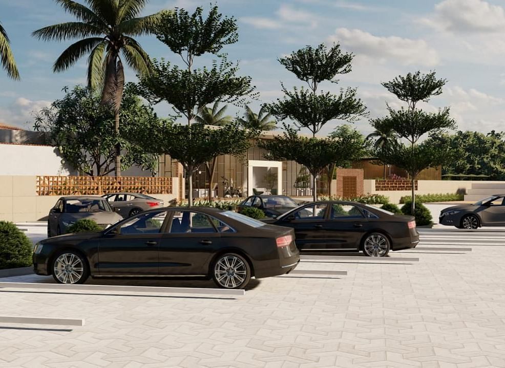 A parking lot with several cars parked, surrounded by palm trees and other greenery, under a bright sky.