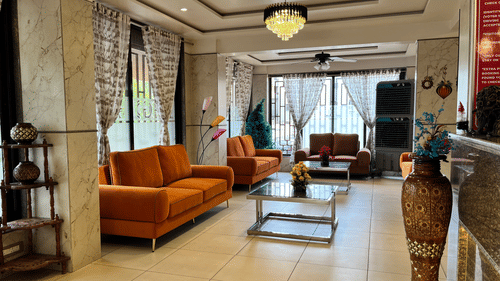 Another angle of the hotel lobby with orange couches placed in front of coffee tables at VITS Select Kharadi, Pune.