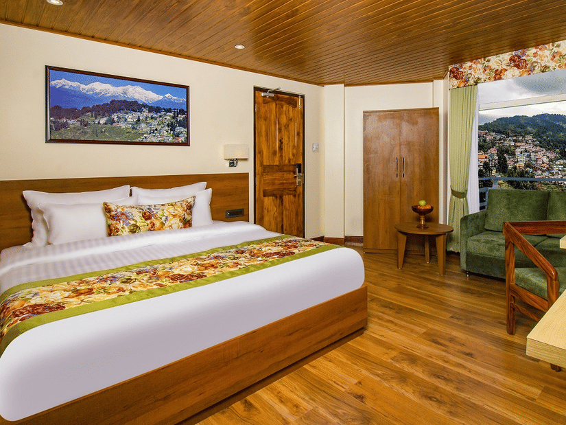 Our room featuring a balcony, warm wooden interiors, a king size bed, seating area, and spacious layout | Mount Lungta - A Darjeeling Hotel with Balcony