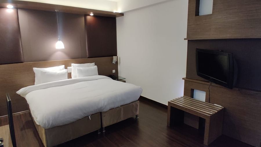 A room with a neatly made bed and a mounted television, showing a comfortable space - VITS Gurugram