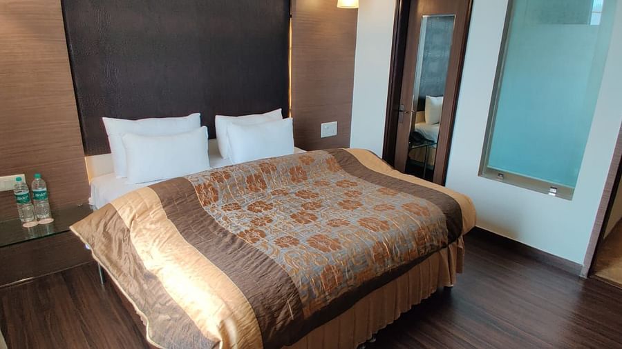 A bedroom with a neatly made bed, dark curtains, and a wooden floor, creating a comfortable space - VITS Gurugram