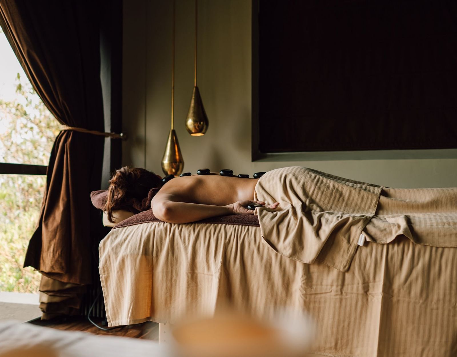 Woman lying on a massage table with hot stones on her back.