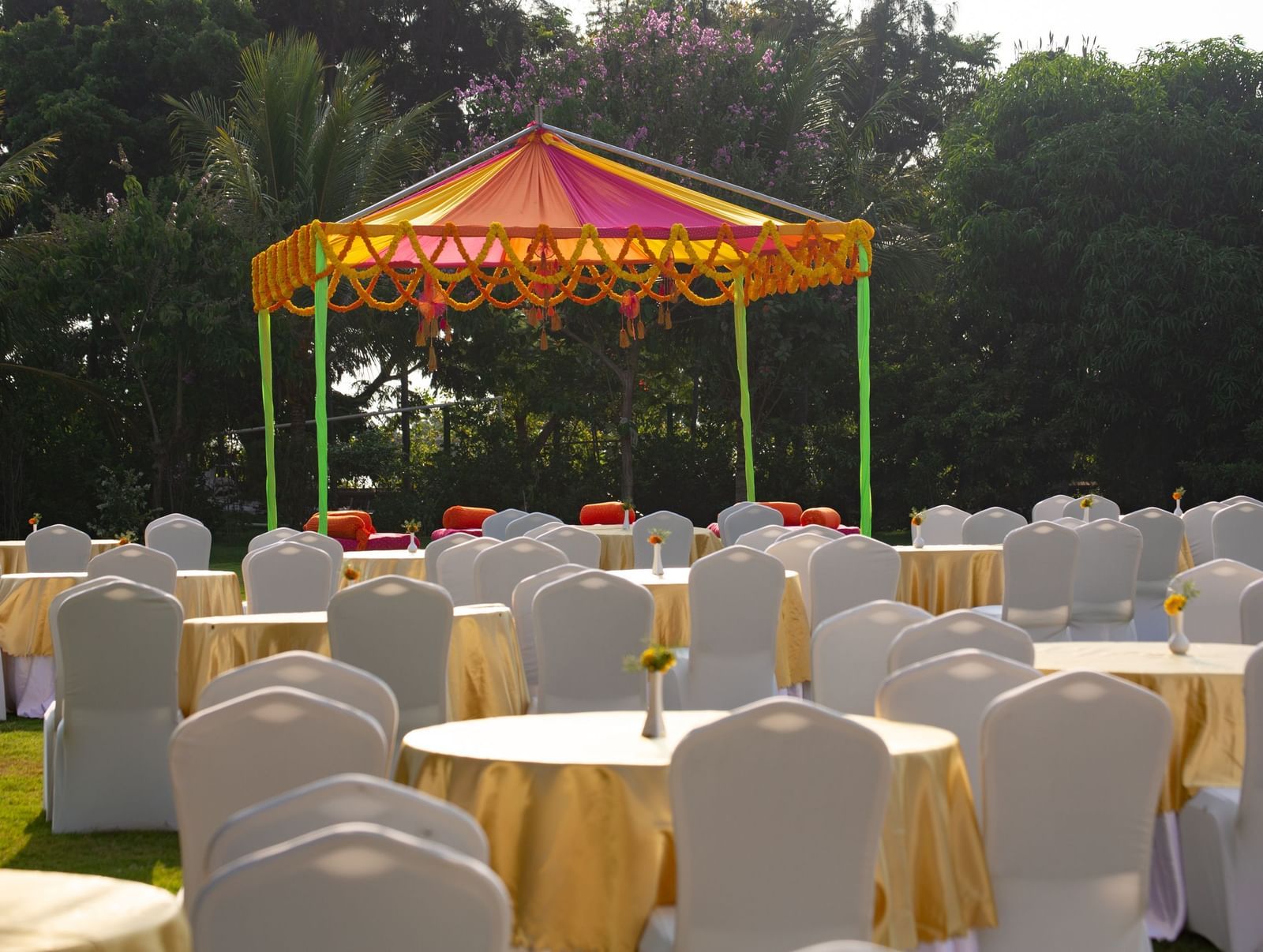 An outdoor event space under a red and yellow tent, with round tables and chairs on a lawn | Citrus Garden | Grand Bay Resort and Spa