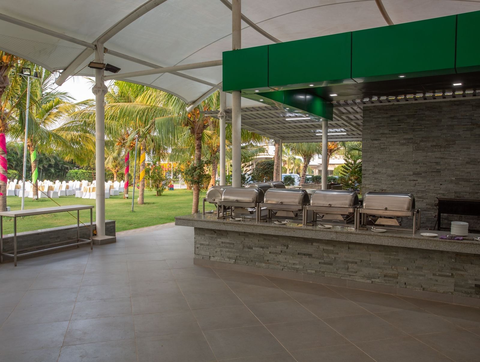 An outdoor catering setup under a large tent, with long buffet tables laden with food warmers | Citrus Garden | Grand Bay Resort and Spa