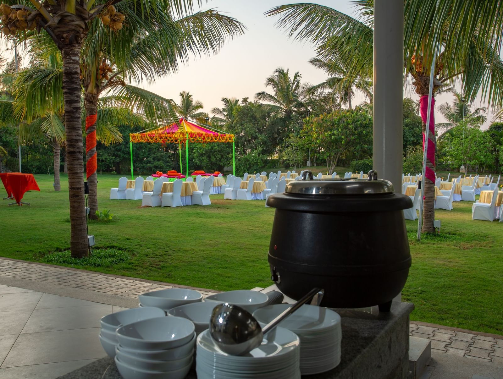 An outdoor catering station on a green lawn with palm trees, featuring a large black soup pot | Citrus Garden | Grand Bay Resort and Spa