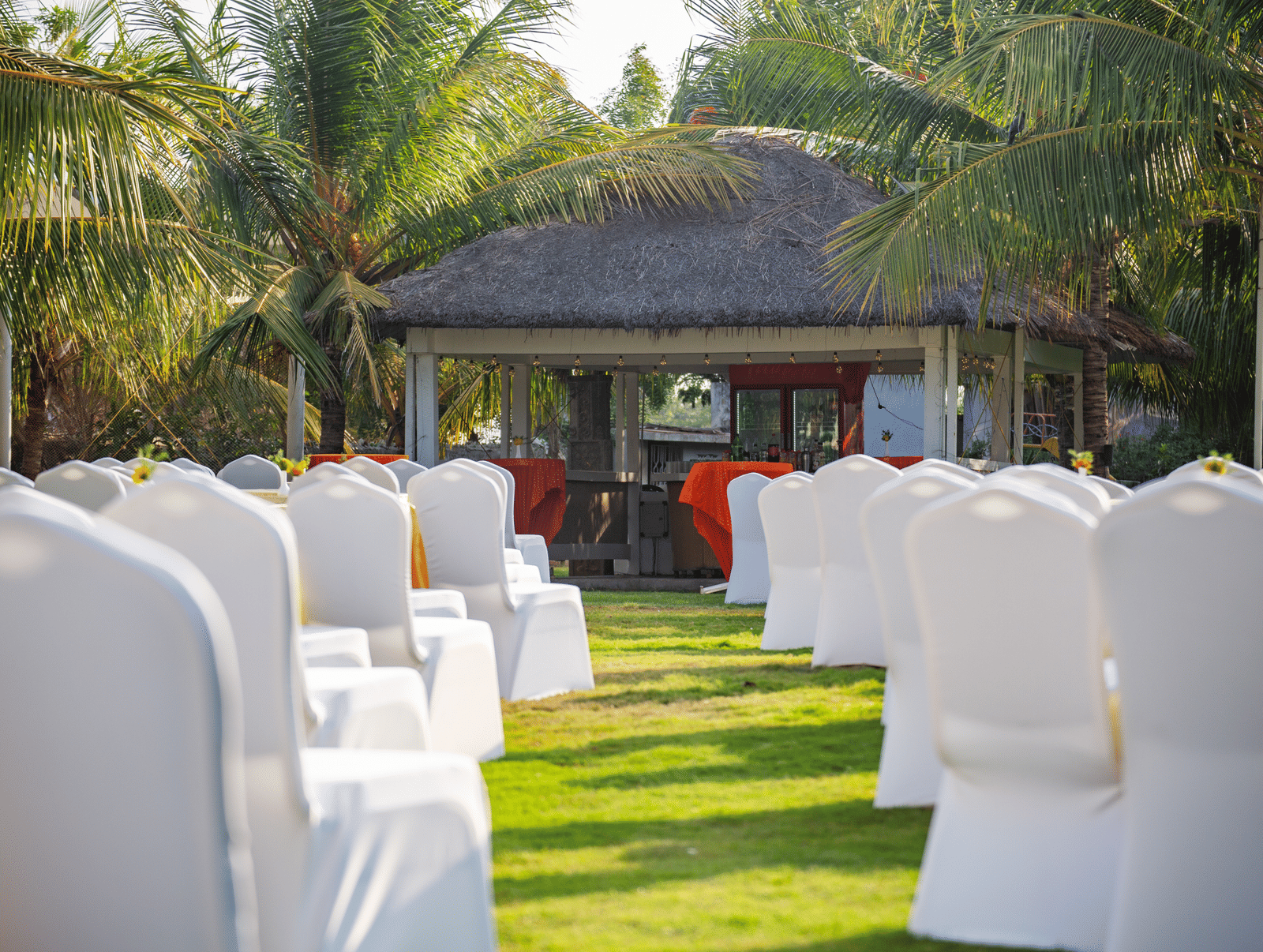 The back view of an outdoor event setup with numerous white chairs facing a shack - Grande Bay Resort & Spa, Mamallapuram