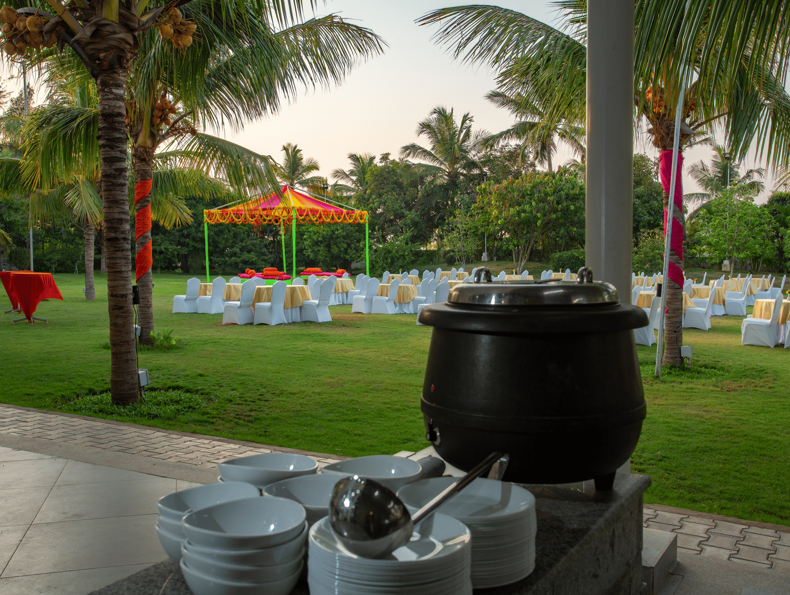 Large chafing dish station arranged for outdoor dining beside a green lawn with event decor - Grande Bay Resort & Spa, Mamallapuram