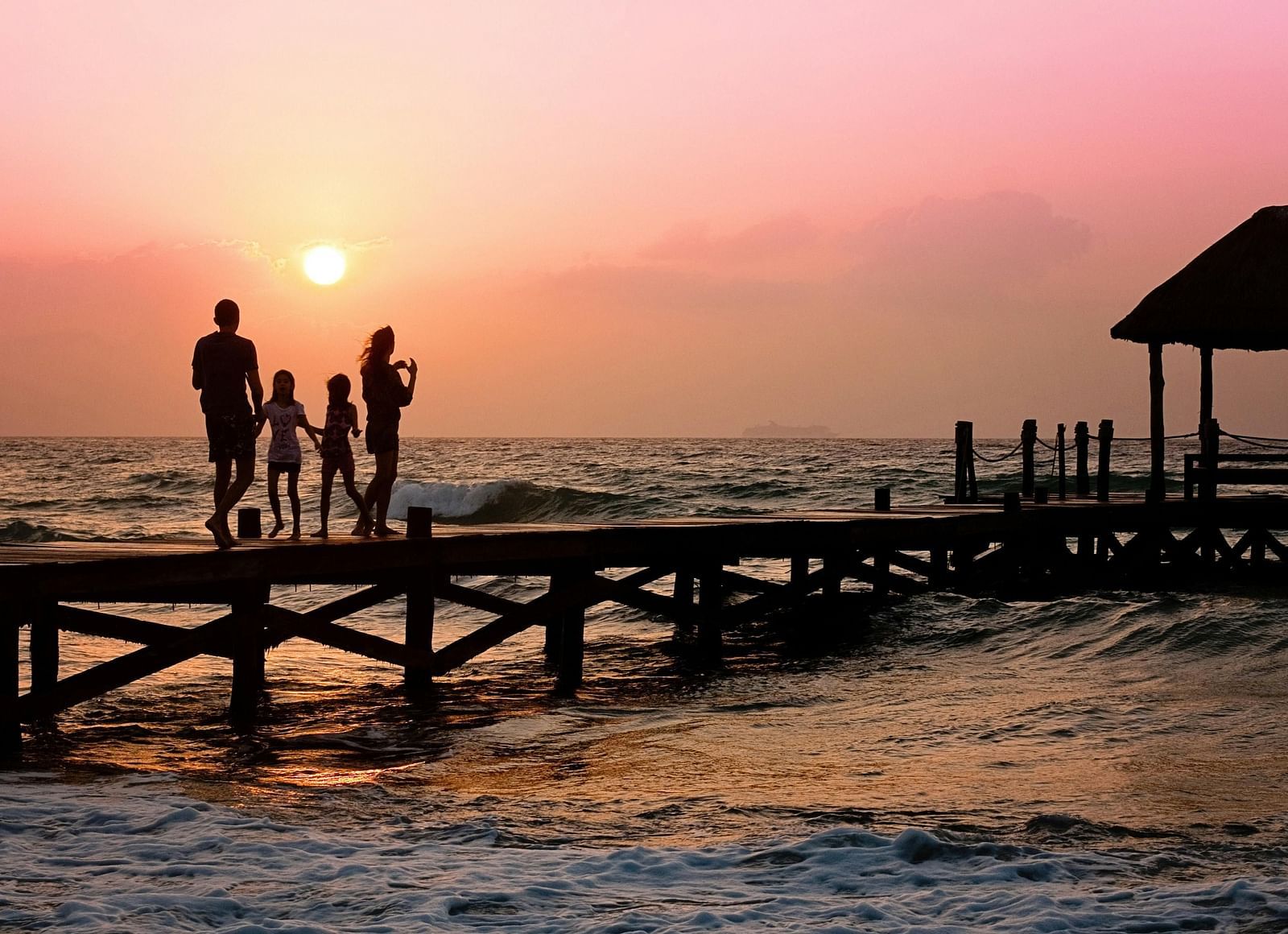 A family walking on a pier during sunset